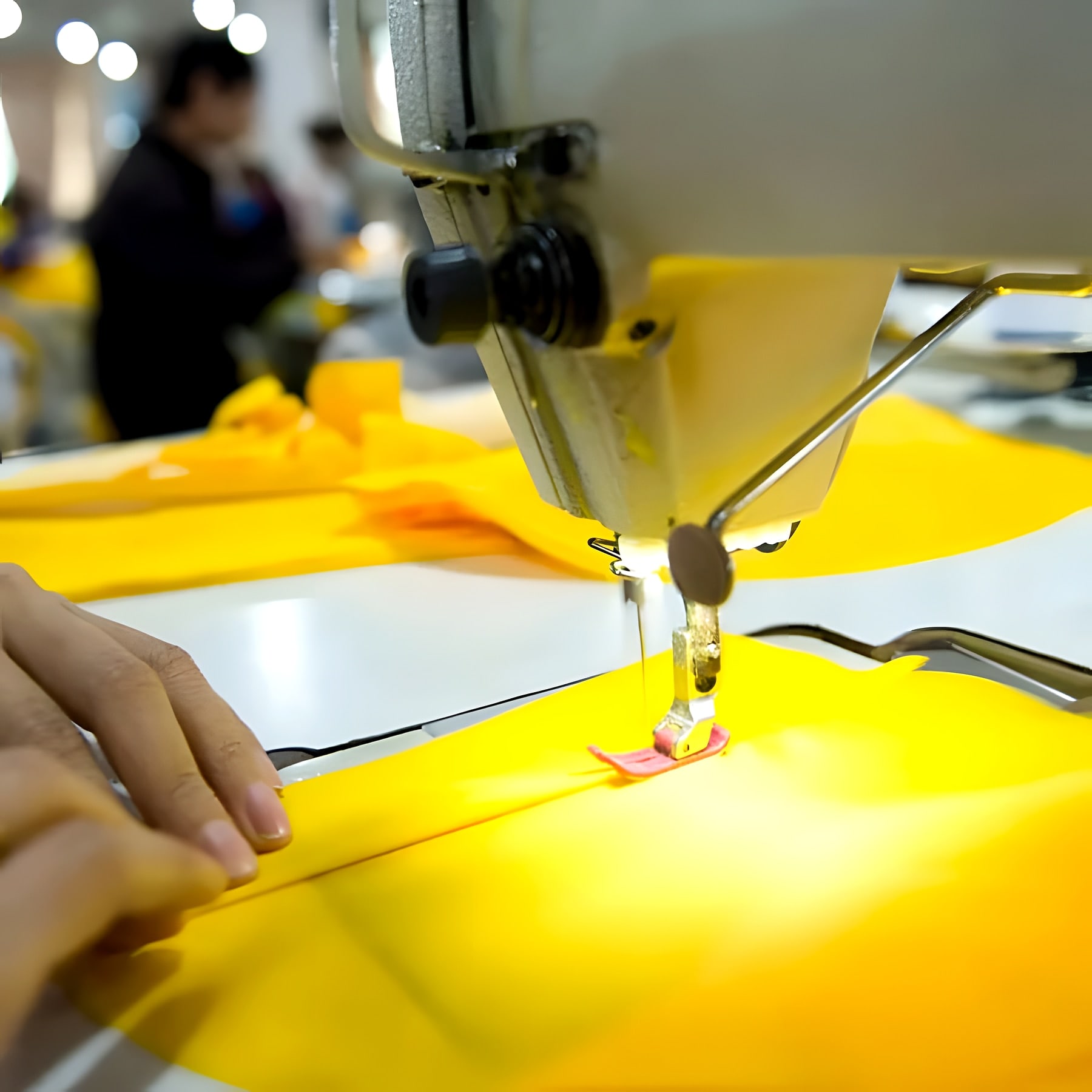 Close-up of a sewing machine needle stitching a yellow panel
